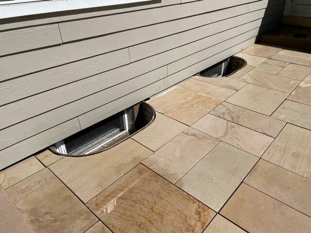 Stone tile paver patio around egress window