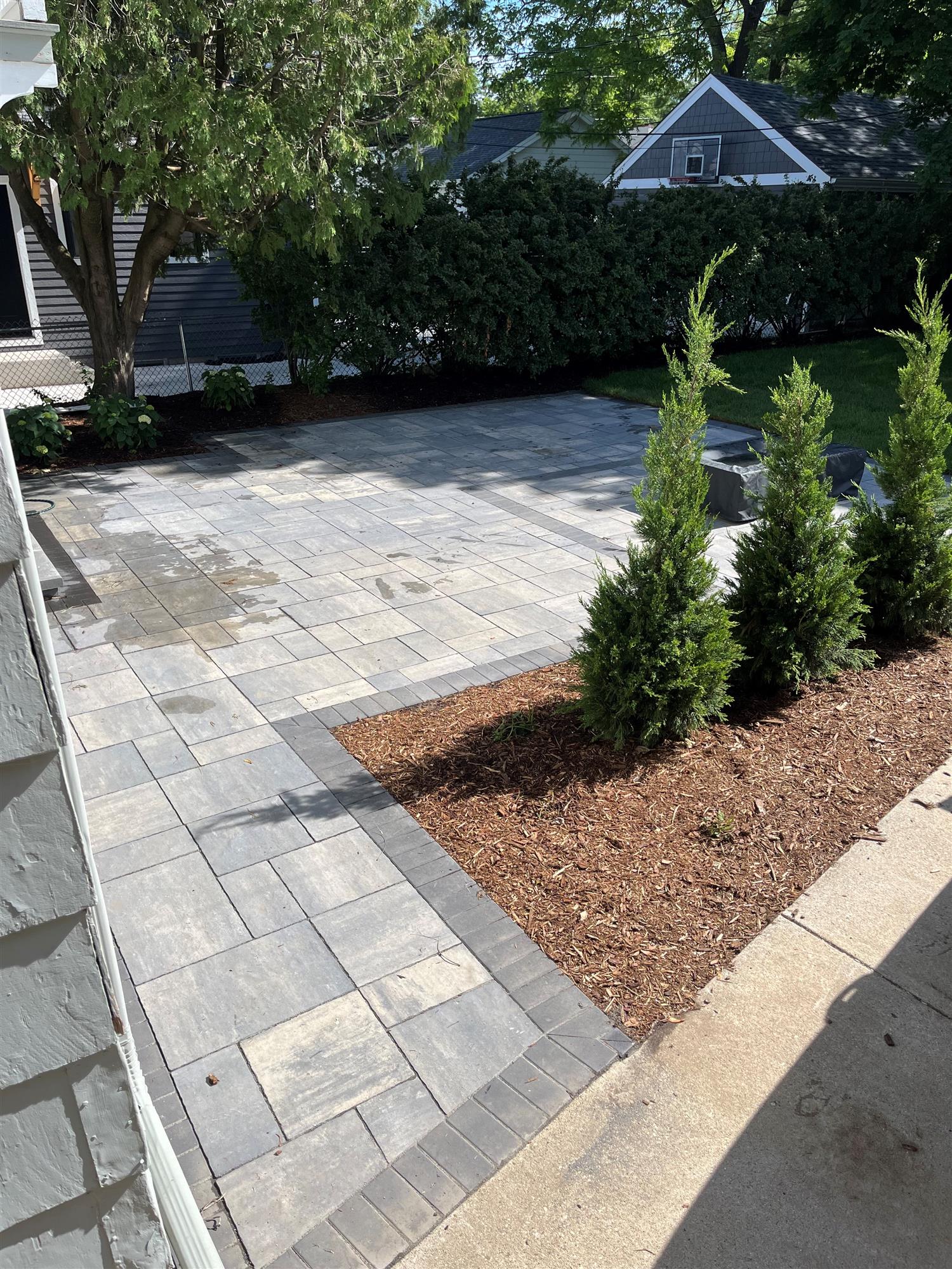 Patio with Tree-Lined Fence and Pine Trees by Driveway