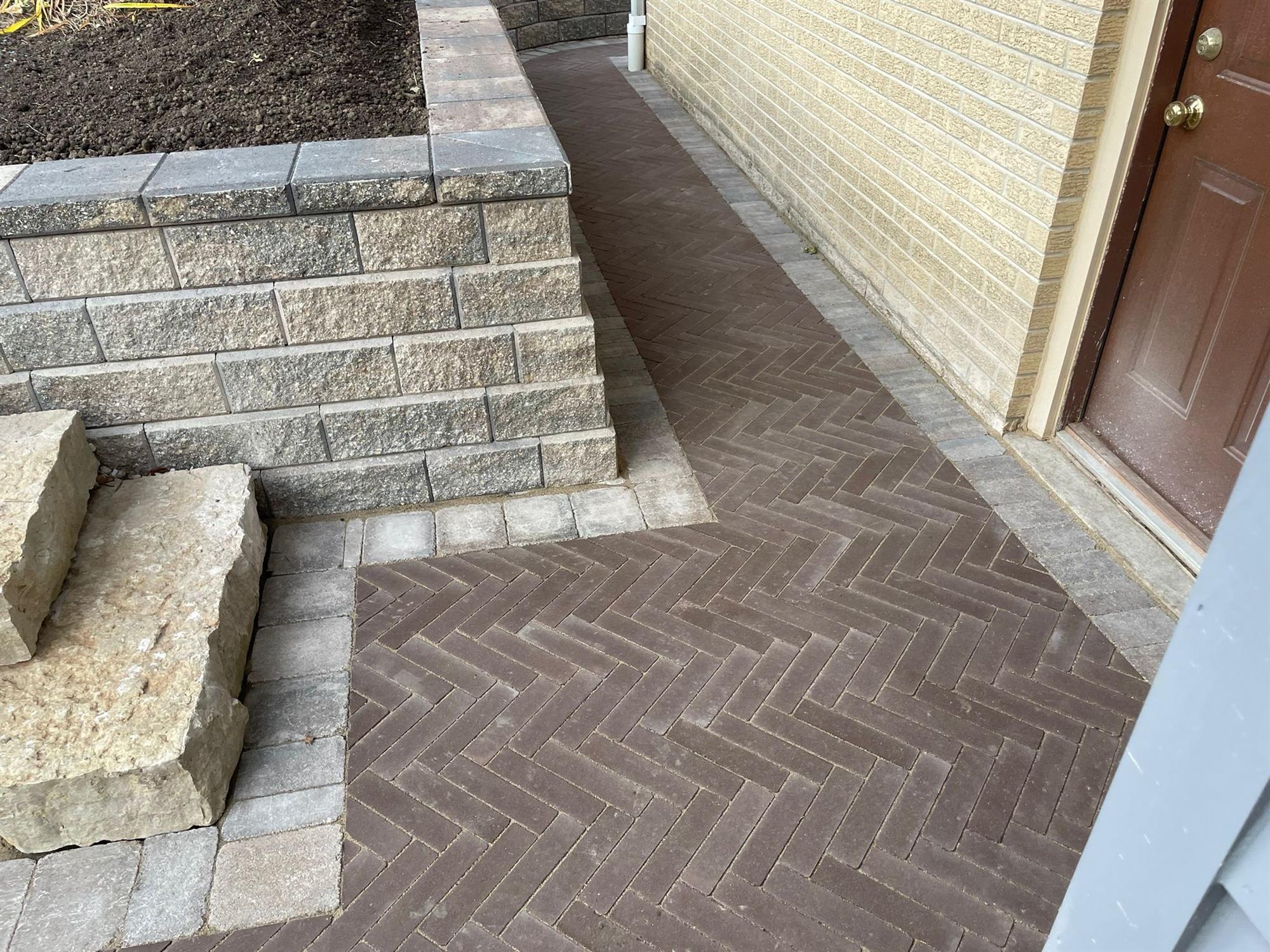 Brick and Stone Walkway around the House Covered by a Retaining Wall
