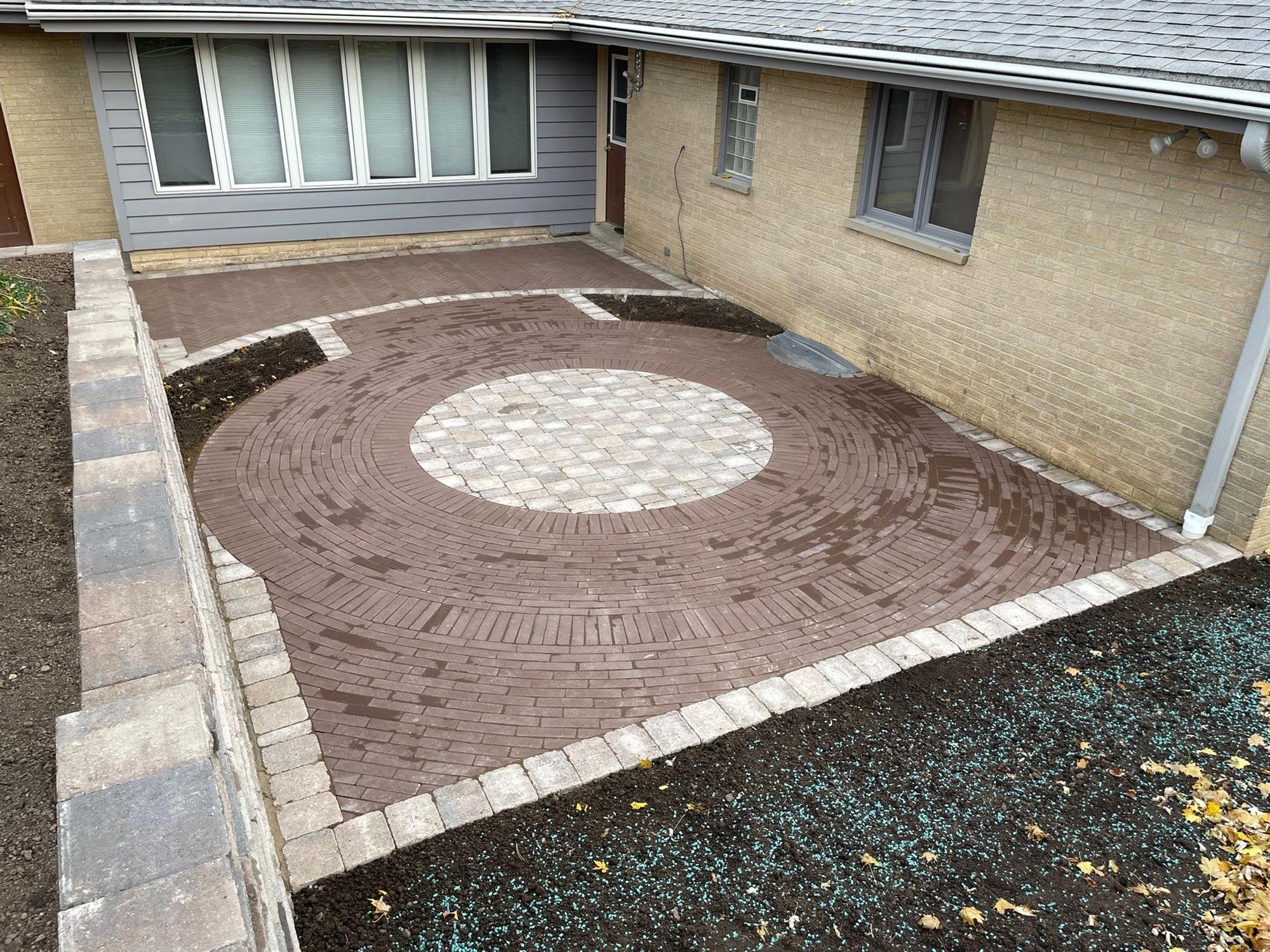 Patio with Circular Pattern with a Retaining Wall Connected to Back Door of the House