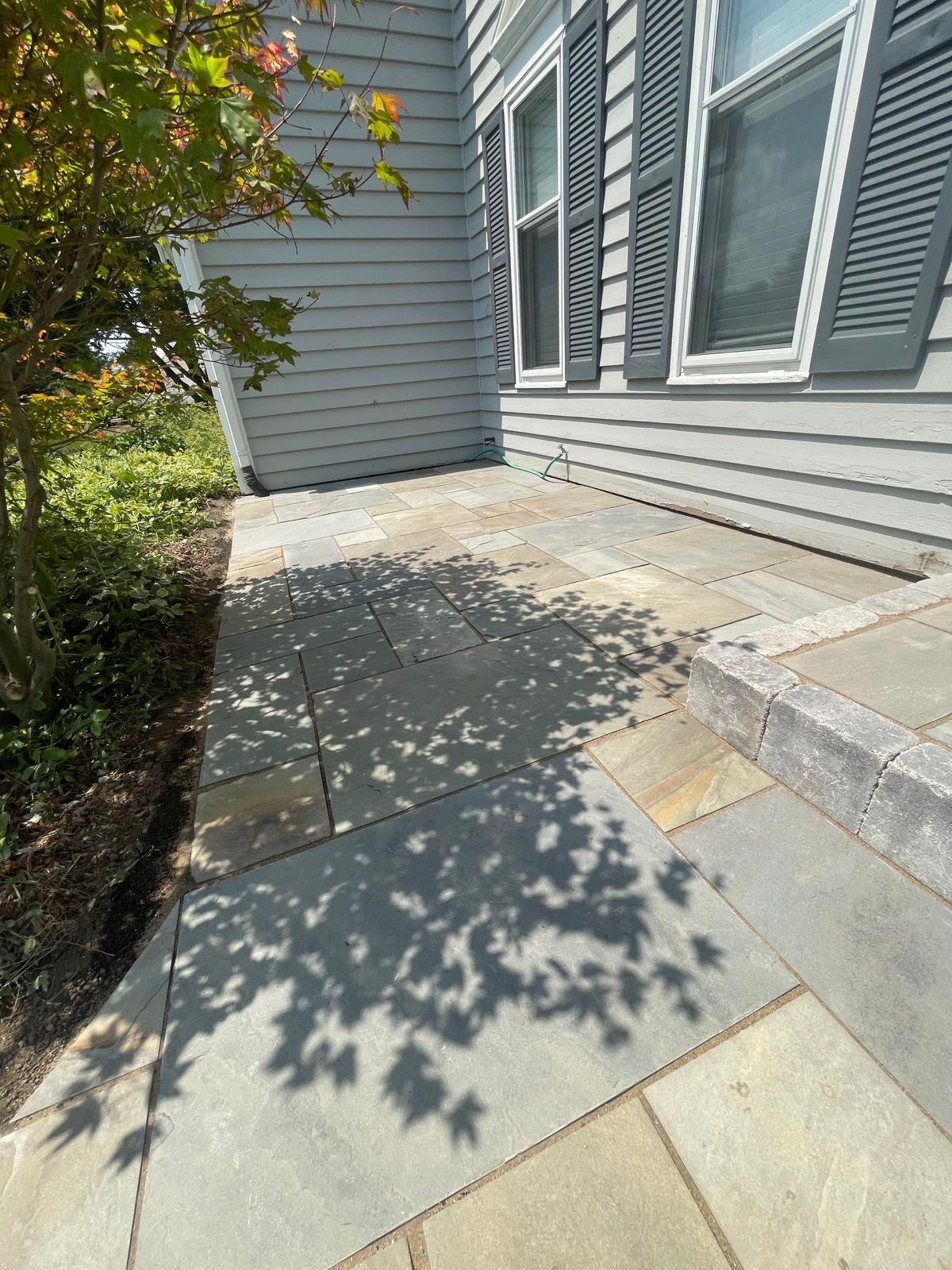 Brick paved patio in the backyard, making use of a corner on the outside of the house.