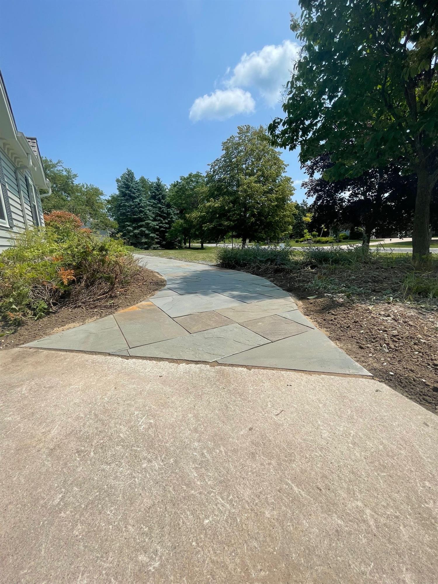 Paved path that wraps around the side of the house