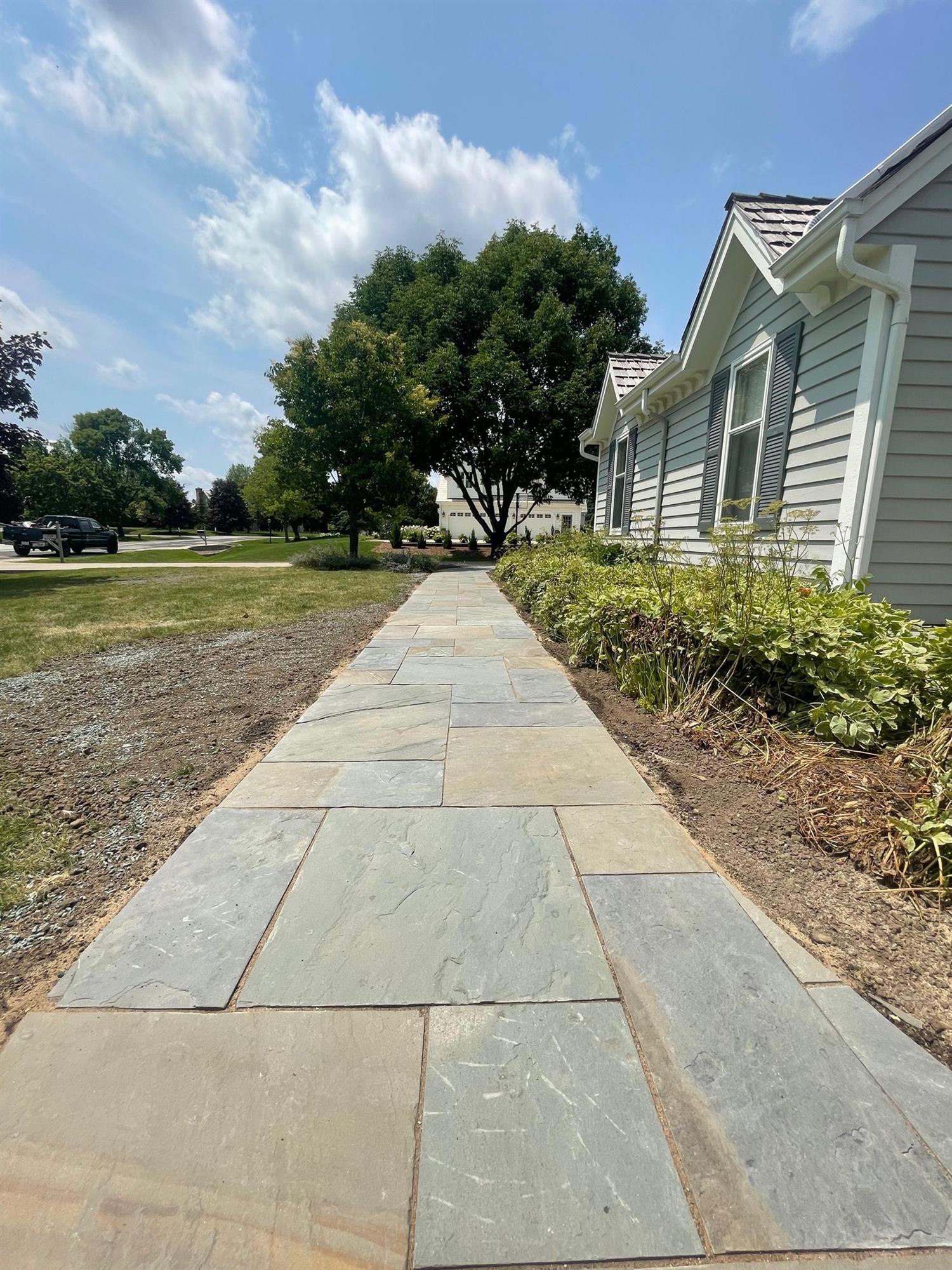 This paved path follows along the side of the house, utilizing natural stone of various colors. 