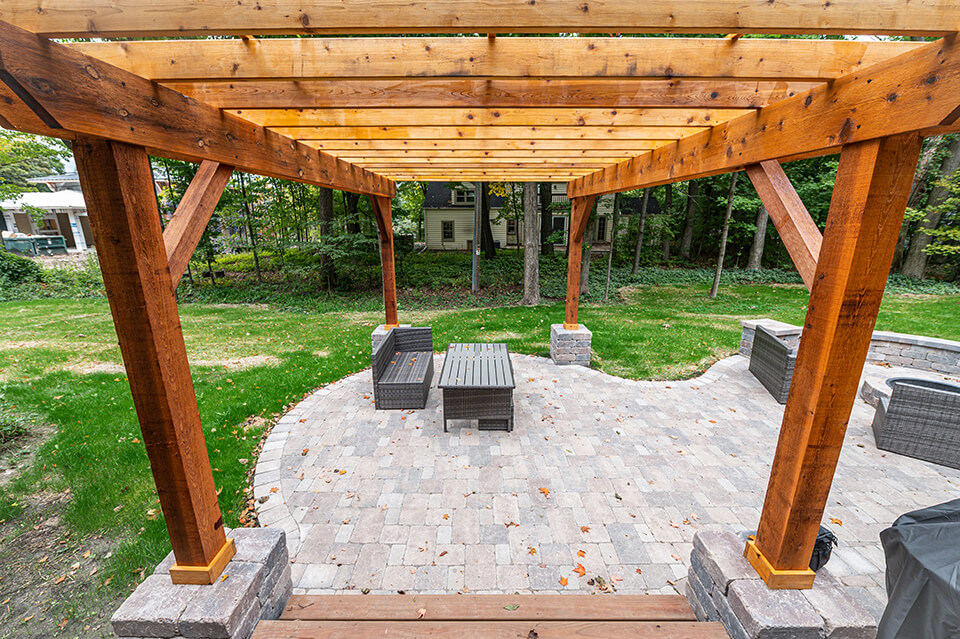 Attached wooden pergola over stone paver patio