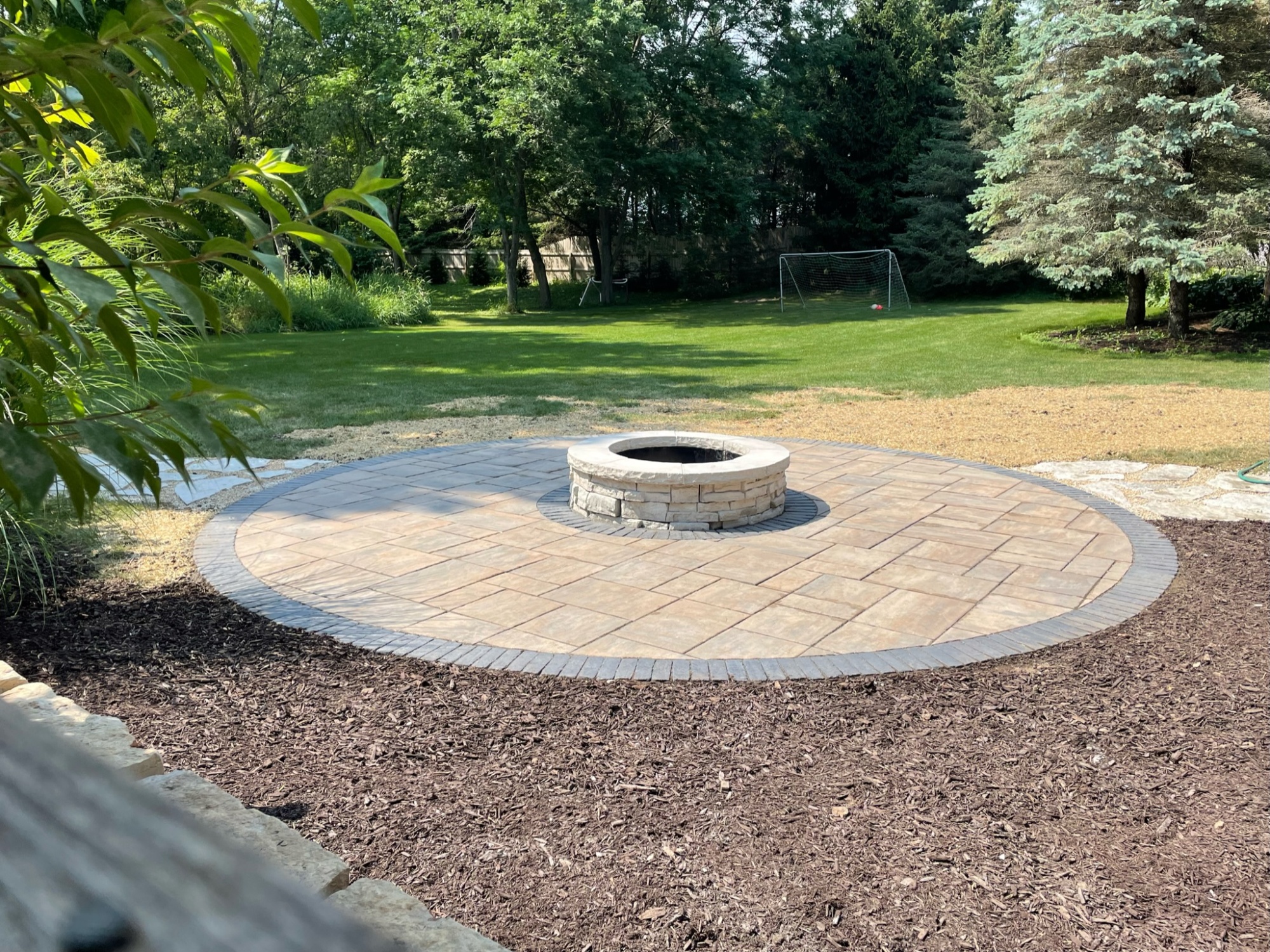 Stone Patio With Firepit in Back Yard